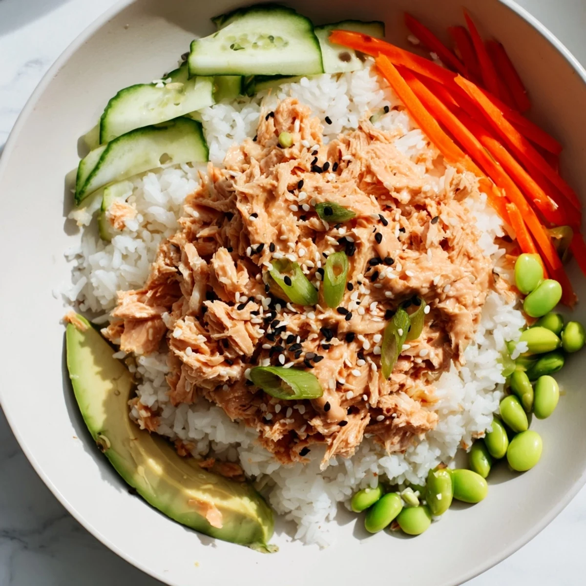 Flaked salmon mixed with sriracha mayo over fluffy rice in a Spicy Canned Salmon Rice Bowl, delicious!