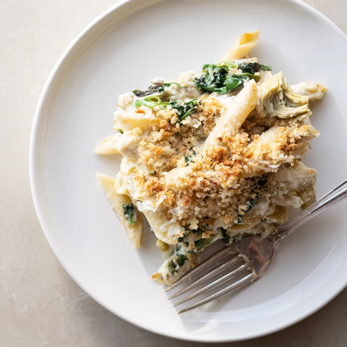 A close-up of golden, bubbling Artichoke Pasta Bake fresh from the oven, with melted Parmesan and crispy breadcrumbs on top.
