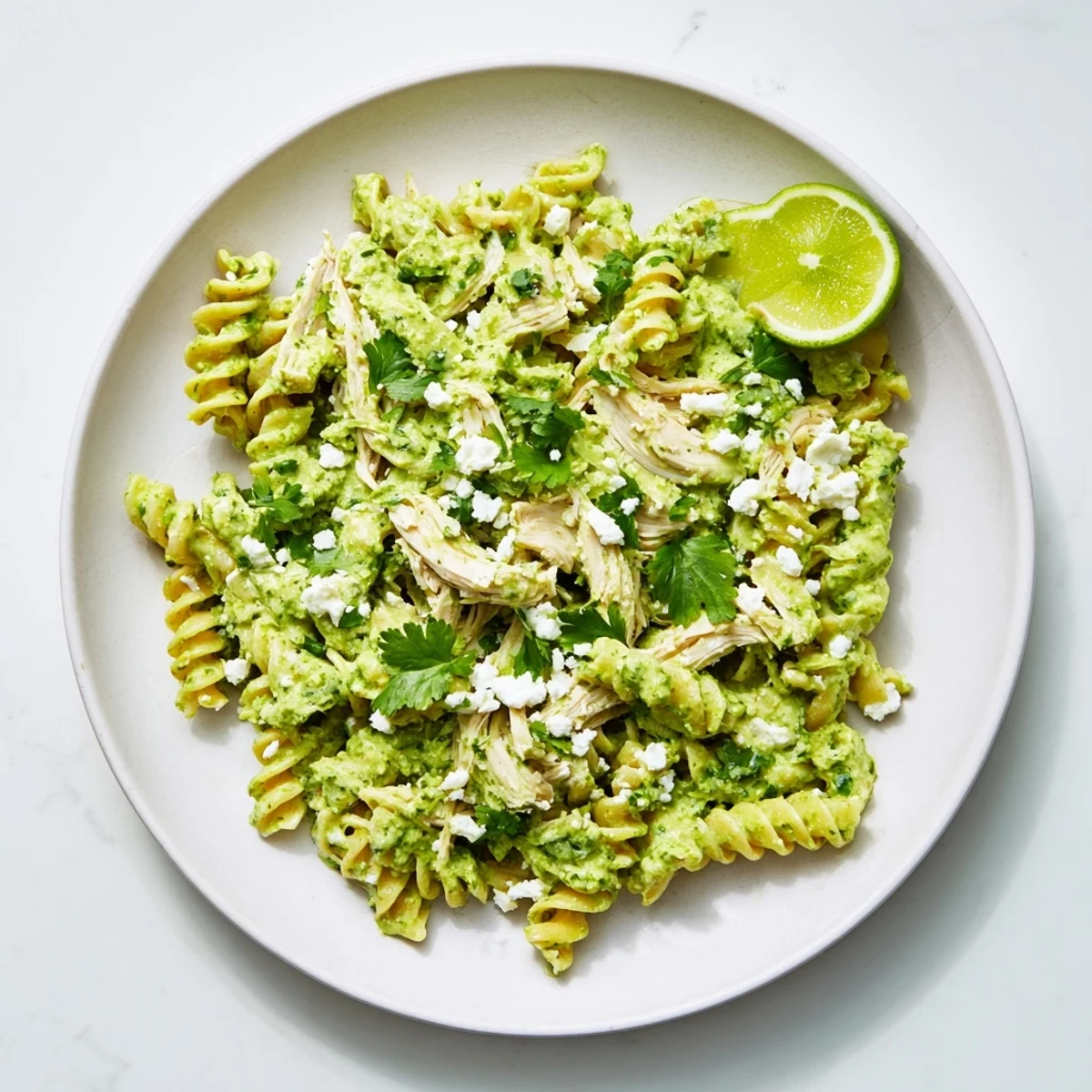 Fresh lime wedges and crumbled cotija cheese garnish this vibrant, high-protein Cilantro Lime Chicken Pasta dinner.