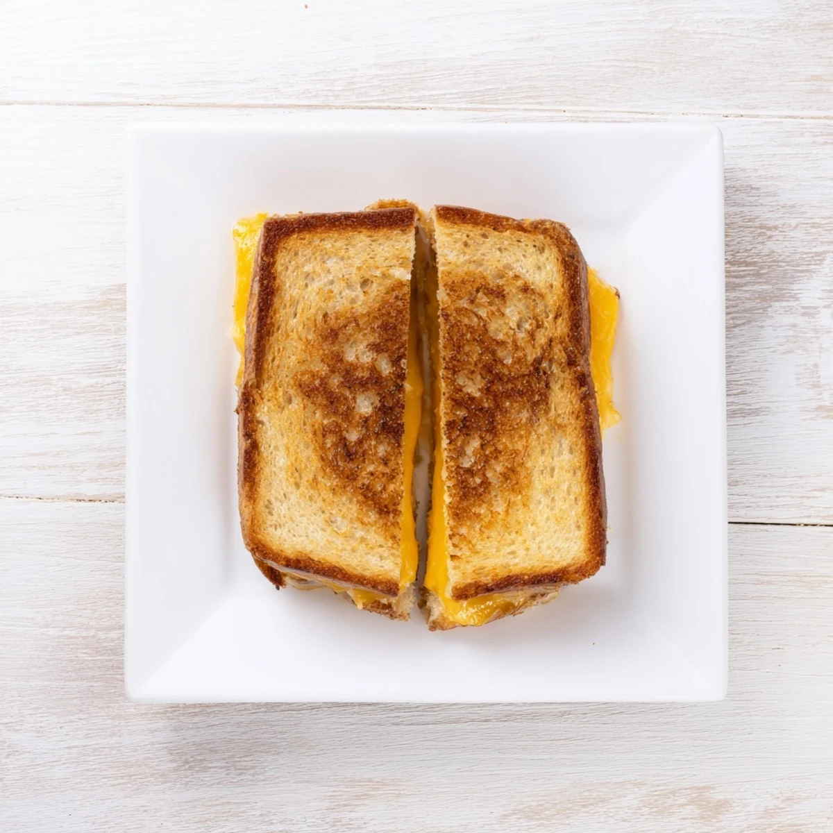 Close-up of a Triple Cheese Sourdough Grilled Cheese on a wooden board, golden crust and gooey cheese filling ready for dipping in tomato soup.