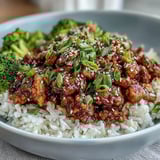 A close-up of Sweet and Spicy Turkey Broccoli Bowls topped with green onions and sesame seeds.