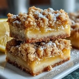 Freshly baked Homemade Lemon Crumb Bars reveal tangy lemon zest and crumbly oat topping on a rustic table.