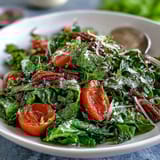 Fresh dandelion greens salad with lemon vinaigrette and Parmesan shavings, topped with cherry tomatoes and toasted pine nuts for a zesty Mediterranean side dish.