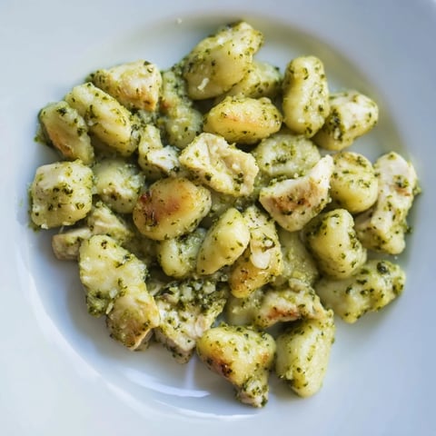 Golden pan-crisped gnocchi and tender chicken cubes coated in a creamy basil pesto sauce, served hot for a comforting Italian dinner.  