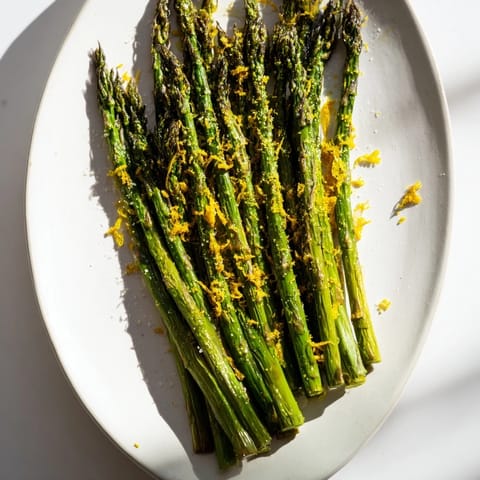 Vibrant photo: perfectly roasted asparagus, topped with tangy lemon zest and Parmesan, ready to eat.