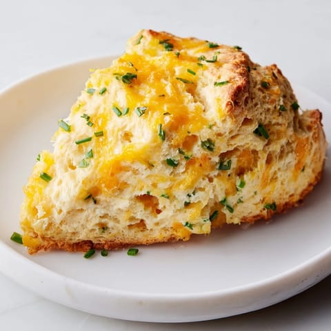 Freshly baked golden cheddar and chive scones with flaky layers, perfect for a cozy brunch.