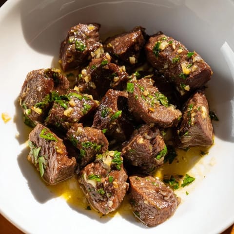 Golden-brown air fryer garlic-butter steak bites, ready to serve with fresh parsley garnish, smelling delicious.