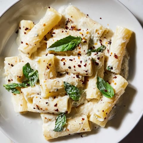 A close-up of creamy cottage cheese pasta, perfectly plated with a vibrant, creamy sauce.