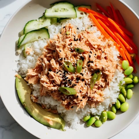 Flaked salmon mixed with sriracha mayo over fluffy rice in a Spicy Canned Salmon Rice Bowl, delicious!