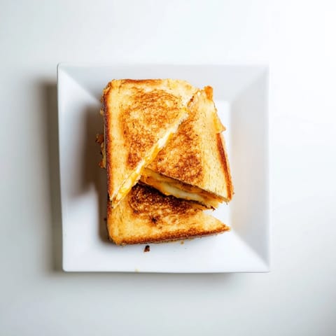 A warm Triple Cheese Sourdough Grilled Cheese sandwich, cut diagonally to reveal layers of melty cheese on buttery sourdough bread.  