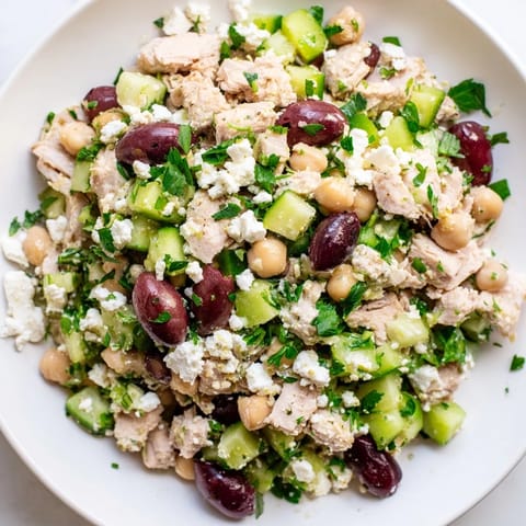 A close-up of Mediterranean Chickpea Chicken Salad shows juicy chicken, creamy feta, and crisp veggies drizzled with zesty dressing.